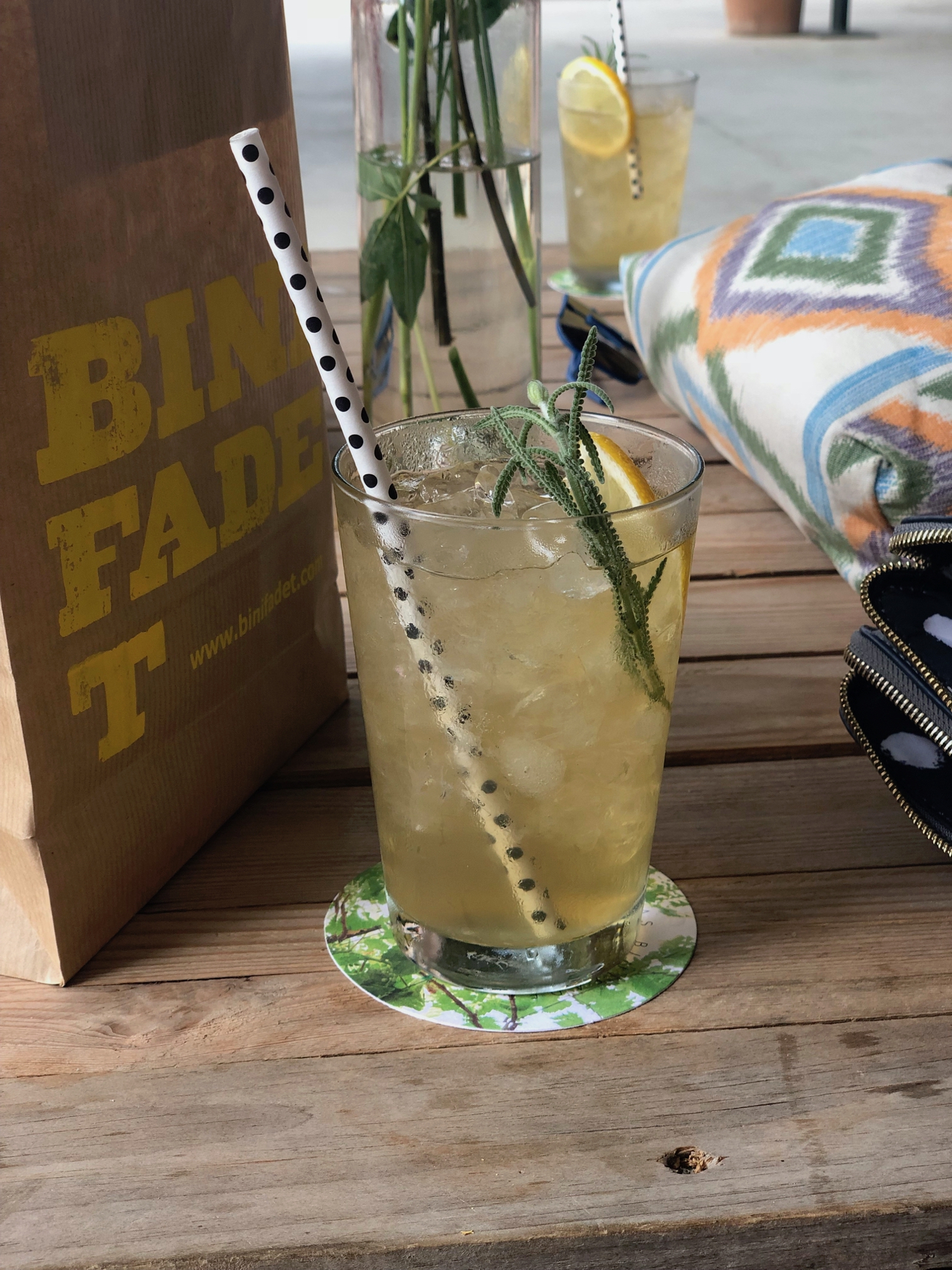 A paper bag with ‘Binifadet’ printed on the side, accompanied by fancy yellow Lavendar Lemonade drink.