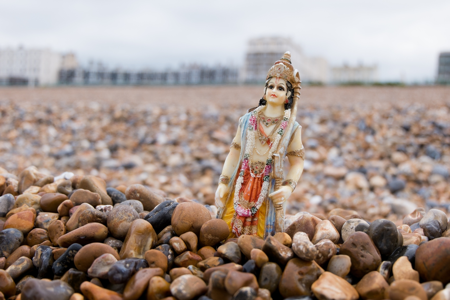A Rama figurine, standing in pebbles on Brighton beach