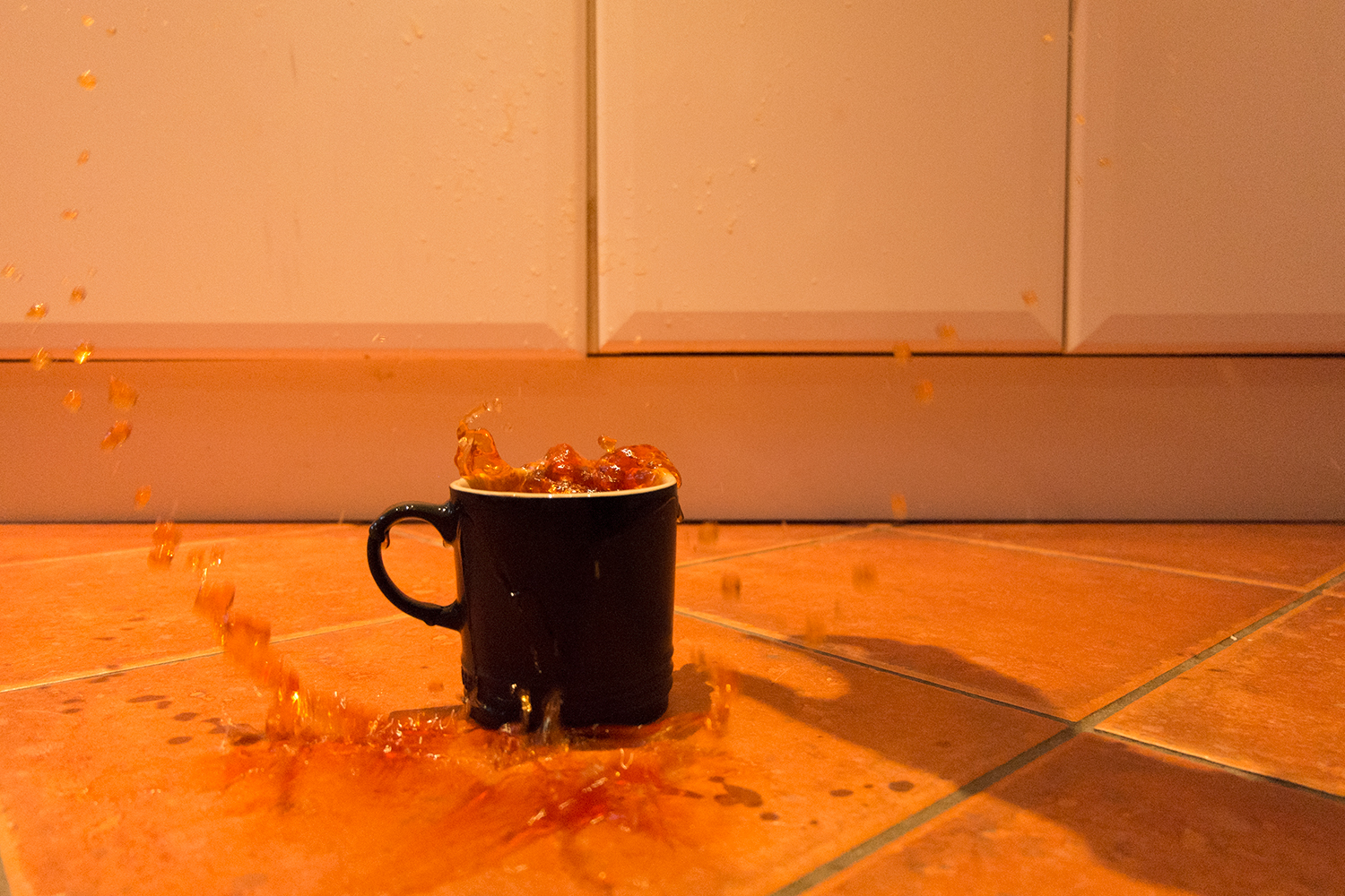 Tea splashing out of a mug on the kitchen floor