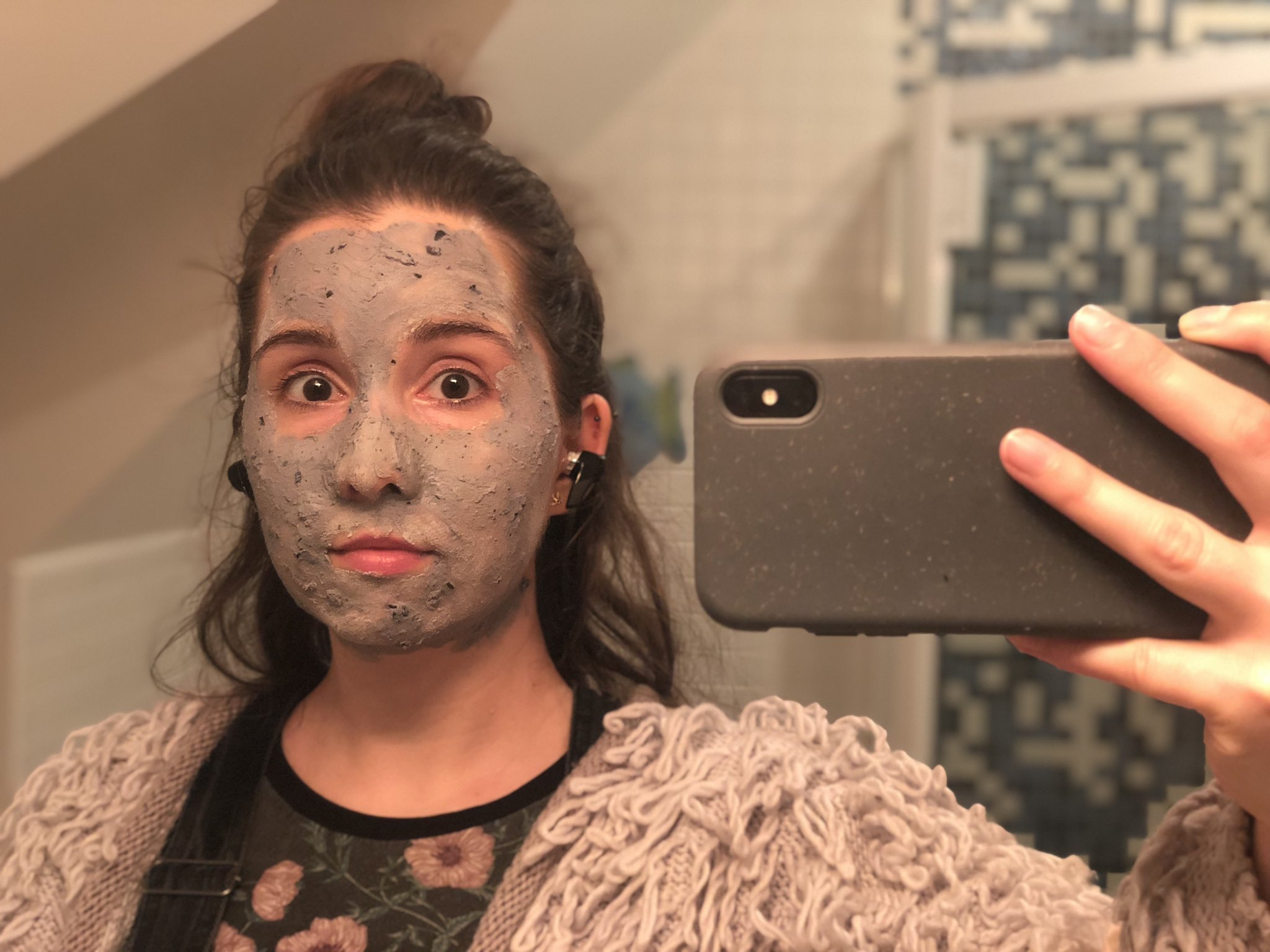 Mirror selfie of me wearing a grey speckled facemask that matches my grey speckled phone case.