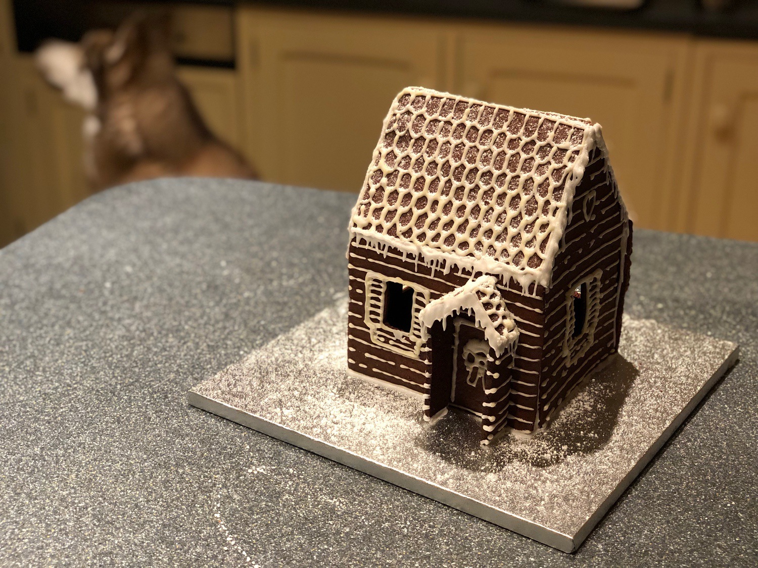 small gingerbread house decorated with icing to look like a log cabin or shack.