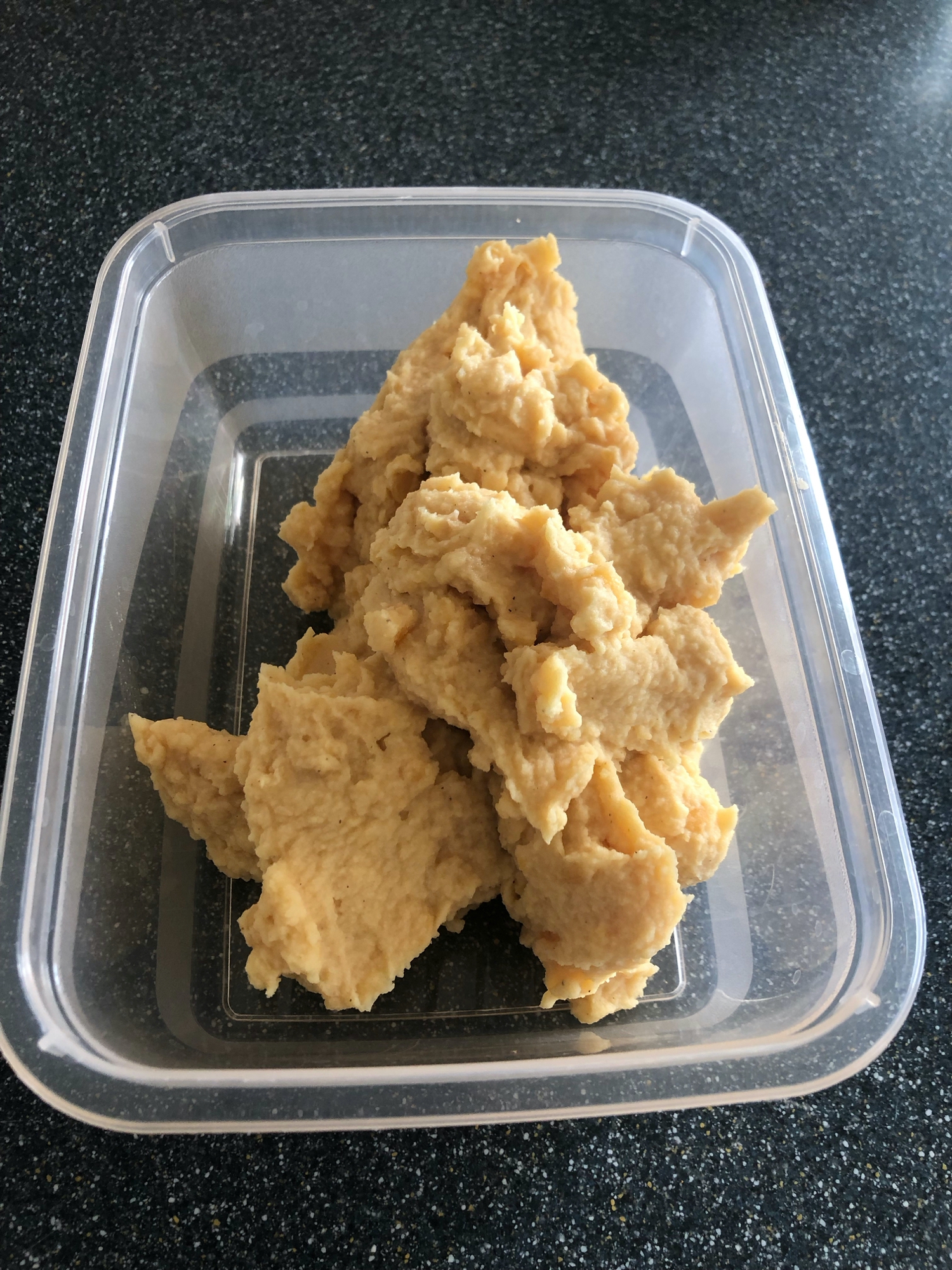 Plastic container filled with thick fluffy beige pease pudding.