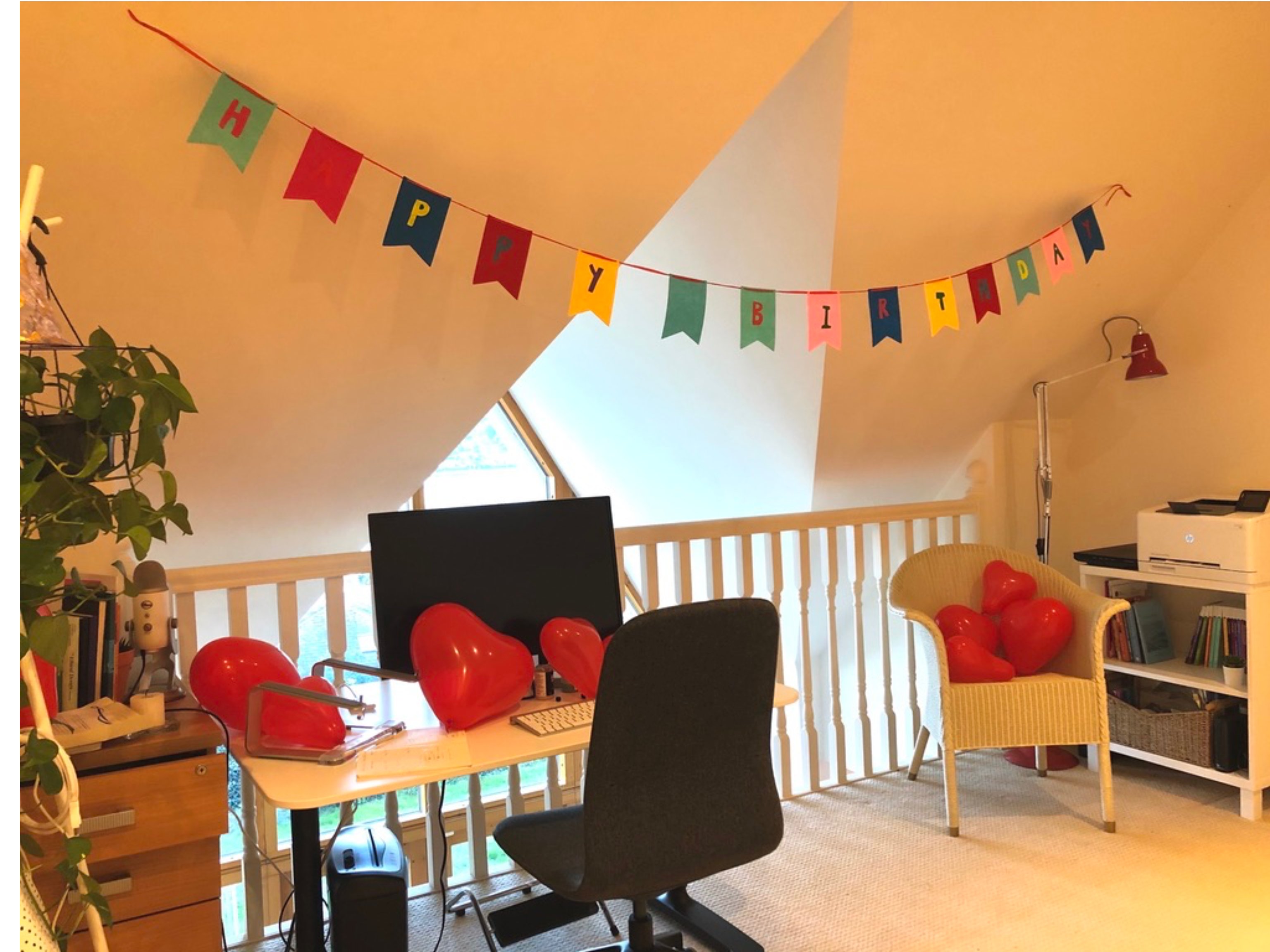 My home office decorated with a happy birthday banner and red heart balloons.